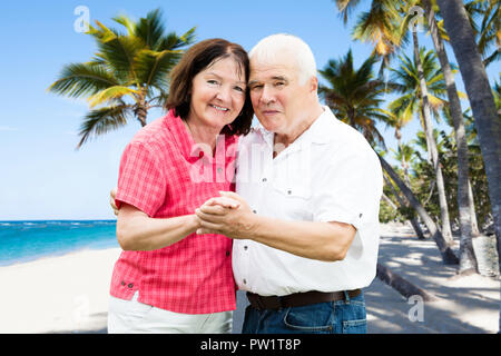 Ritratto di una coppia Senior Holding Hands Ta Beach Foto Stock