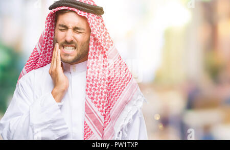 Giovane uomo bello indossare keffiyeh su sfondo isolato di toccare la bocca con la mano con espressione dolorosa a causa di mal di denti o malattie dentali o Foto Stock