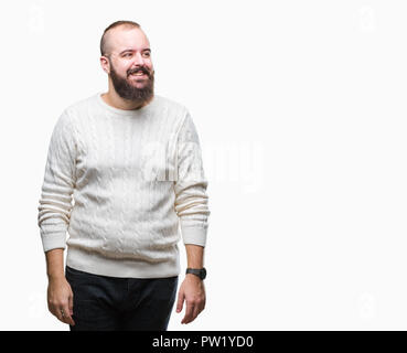 Giovani tanga caucasica uomo che indossa un maglione invernale su sfondo isolato che guarda lontano a lato con il sorriso sul volto, espressione naturale. Ridendo conf Foto Stock