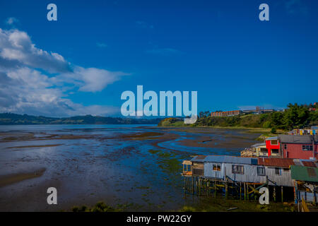 Veduta esterna del coorful belle case in legno su palafitte palafitos, in una bassa marea vista giorno di una splendida giornata di sole a Castro, Isola di Chiloe Foto Stock