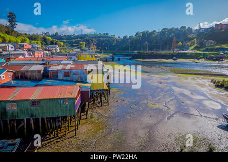 Veduta esterna del coorful belle case in legno su palafitte palafitos, in una bassa marea vista giorno di una splendida giornata di sole a Castro, Isola di Chiloe Foto Stock