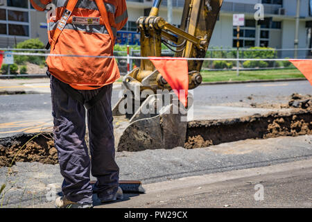 I lavoratori di scavare fino alla strada per stabilire nuove tubazioni Foto Stock