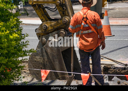 I lavoratori di scavare fino alla strada per stabilire nuove tubazioni Foto Stock