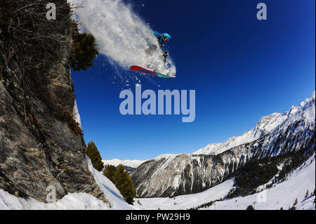 Uno snowboarder salta fuori da una scogliera in francese resort alpino di Courchevel. Cielo blu, polvere, fuoripista. Foto Stock