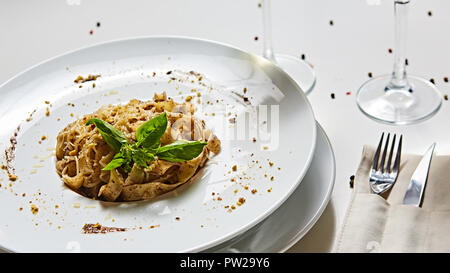 Tagliatelle con funghi e decorate con foglie di basilico. Foto Stock