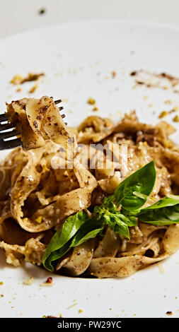 Tagliatelle con funghi e decorate con foglie di basilico. Foto Stock