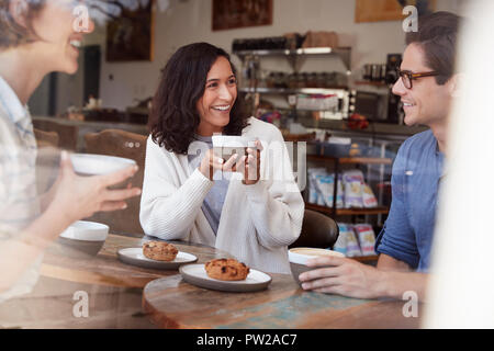Tre giovani amici adulti parlando di bere il caffè al caffè Foto Stock