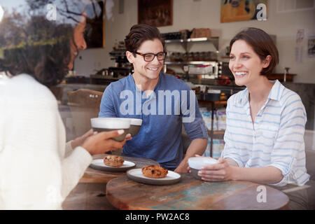 Tre amici di parlare e di bere il caffè in una caffetteria Foto Stock