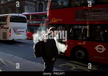 Un vaper espira prima di salire a bordo di un bus durante la serata l'ora di punta nella capitale, il 3 ottobre 2018, a Londra, in Inghilterra. Foto Stock