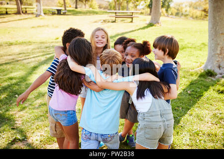 Un gruppo di ragazzi in età scolare in un huddle all'aperto, vista posteriore Foto Stock