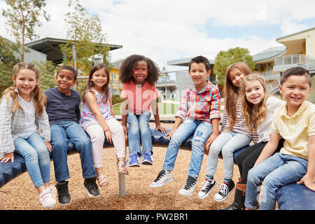 Scuola elementare i bambini seduti sulla giostra in schoolyard Foto Stock