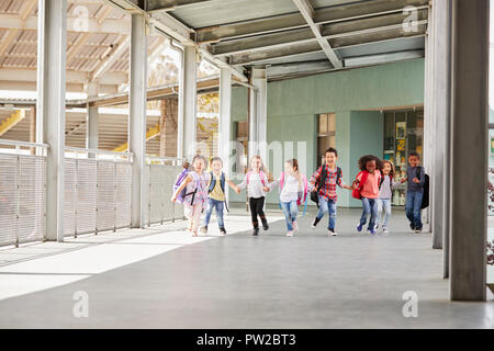La scuola primaria kids eseguire tenendo le mani nel corridoio della scuola Foto Stock