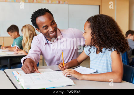 Maschio di insegnante di scuola elementare e una ragazza in classe, close up Foto Stock