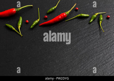 Il cibo piccante sfondo presentazione peperoncino rosso e peperoncino verde su nero ardesia board Foto Stock