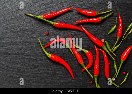 Il cibo piccante sfondo presentazione peperoncino rosso e peperoncino verde su nero ardesia board Foto Stock