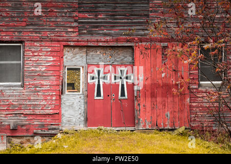 Red barn double porte sono adornate in grande stile gotico-style attraversa circondato dalla caduta delle foglie Foto Stock