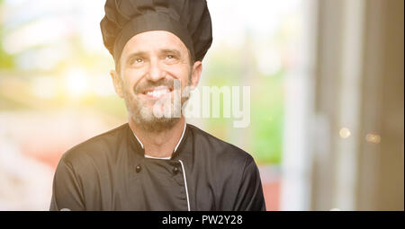 Senior uomo cook, indossando chef hat il pensiero e la ricerca di esprimere dubbi e meraviglia Foto Stock