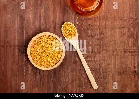 Un sano cibo biologico. Un top shot di polline, un vasetto di miele e un cucchiaio di legno al buio su un sfondo rustico con copyspace Foto Stock