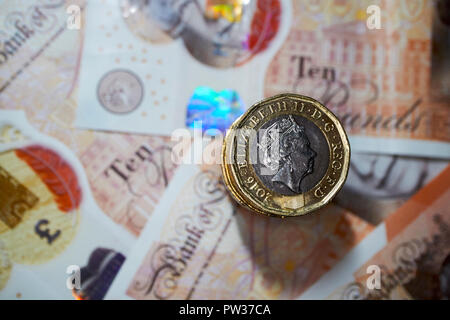 Pila di libbra di monete su plastica dieci pound note Foto Stock
