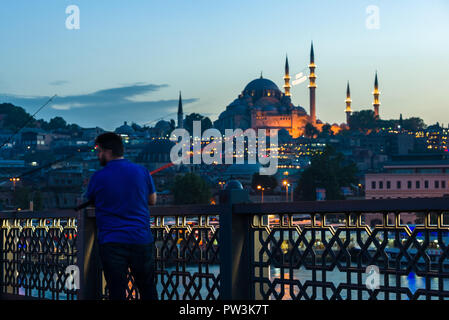 Un pescatore di pesci da Ponte Galata al tramonto con la moschea di Suleymaniye in background, Istanbul, Turchia Foto Stock