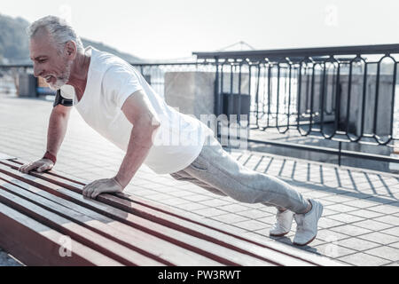 Felice la persona di sesso maschile facendo push-up Foto Stock