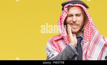 Giovane bello arabian uomo con capelli lunghi che indossa keffiyeh su sfondo isolato di toccare la bocca con la mano con dolorose espressione perché di tootha Foto Stock