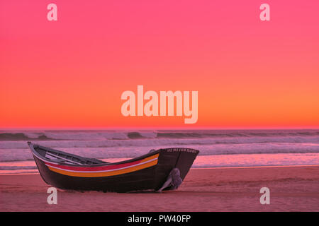 Un pittoresco imbarcazione in legno ad una spiaggia dorata di Lisbona al tramonto Foto Stock