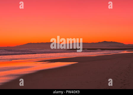 Un pittoresco arancione tramonto in una spiaggia dorata di Lisbona Foto Stock