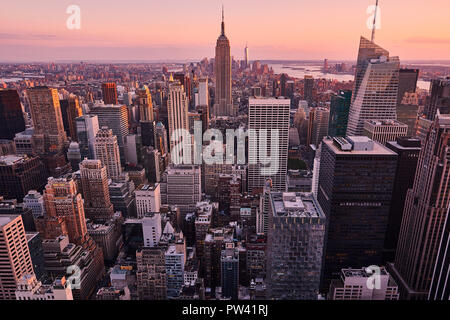 Una vista panoramica di Manhattan, New York, NY, gli Stati Uniti. Il riflesso giallo del tramonto si trova sugli edifici degli uffici. Le luci della città sono spente e la città sembra morta. Foto Stock