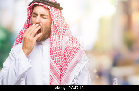 Giovane uomo bello indossare keffiyeh su sfondo isolato annoiati sbadigli stanchi che copre la bocca con la mano. Inquieto e sonnolenza. Foto Stock