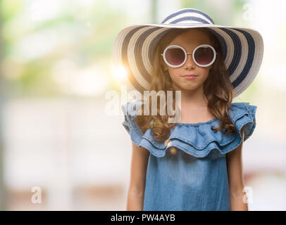 Bruna ragazza ispanica indossando occhiali da sole e cappello estivo con un fiducioso espressione sul viso intelligente pensare grave Foto Stock