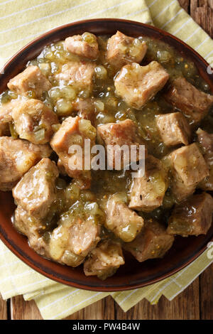 Carne di maiale messicano Cile Verde è fatta di gara di pezzi di carne di maiale cotto a fuoco lento in una saporita tomatillo e brodo di Cile closeup su una piastra sul tavolo. In verticale Foto Stock