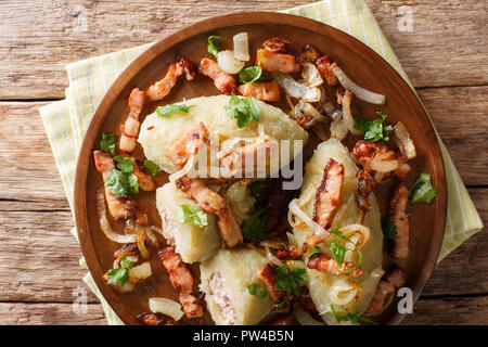 Baltic Cepelinai gnocchetti di patate con ripieno di carne serviti con pancetta e cipolle fritte close-up sul tavolo. parte superiore orizzontale vista da sopra Foto Stock