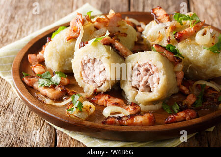 Baltic Cepelinai gnocchetti di patate con carne macinata servita con pancetta, prezzemolo e cipolle fritte close-up su una piastra sul tavolo orizzontale. Foto Stock