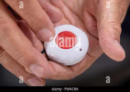 Close-up di una mano di un uomo premendo il pulsante di allarme di emergenza per Foto Stock