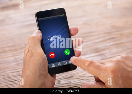 Close-up di un anziano uomo di mano azienda Smartphone con chiamata in arrivo Foto Stock