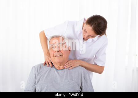 Femmina giovane fisioterapista massaggiatore uomo Senior della spalla in clinica Foto Stock