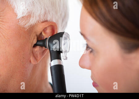 Close-up di un medico donna esame maschio Senior orecchio del paziente con otoscopio Foto Stock