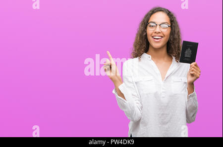 Giovane donna ispanica holding passaporto del Canada molto felice rivolto con la mano e le dita per lato Foto Stock