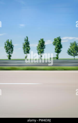 Movimento sfocate di alberi contro il cielo blu visto attraverso la finestra auto Foto Stock