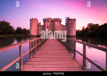 Il Castello di Bodiam, East Sussex, al tramonto con il tramonto del sole e cielo lilla con riflessi nel fossato Foto Stock