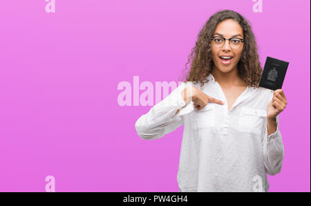 Giovane donna ispanica holding passaporto del Canada con sorpresa faccia puntare il dito a se stesso Foto Stock