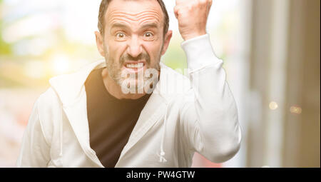 La mezza età uomo di indossare abbigliamento sportivo irritato e arrabbiato esprimendo emozione negativa, arrabbiato con qualcuno Foto Stock