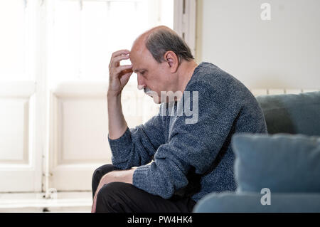 Senior vecchio uomo sensazione disperata triste guardando preoccupato premuto riflessivo e solitaria sul lettino a casa in invecchiamento della salute mentale problemi personali e Lif Foto Stock