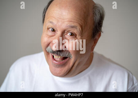 A sorridere e ridere 60s anno vecchio uomo senior candide close up ritratto in emozioni umane e le espressioni del viso concetto isolato in uno sfondo neutro. Foto Stock