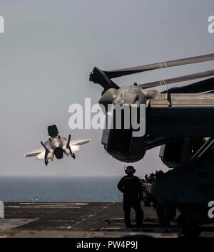 Mare Arabico- U.S. Marines e marinai con il XIII Marine Expeditionary Unit (MEU), Essex anfibio gruppo pronto (ARG), osservare un F-35B Lightning II con Marine Fighter Squadron di attacco 211, togliere dal Wasp-classe assalto anfibio nave USS Essex (LHD 2), il 5 ottobre 2018. L'Essex è il fiore all' occhiello per la Essex ARG e, con l'avviato XIII MEU, è distribuito negli Stati Uniti Quinta Flotta area di operazioni a sostegno di operazioni navali per garantire stabilità marittimo e la sicurezza nella regione centrale di collegamento del Mediterraneo e del Pacifico attraverso l'Oceano Indiano occidentale e tre st Foto Stock