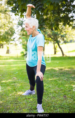 Ritratto di donna senior facendo esercizi streching nel parco Foto Stock