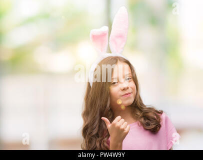Bruna ragazza ispanica che indossa la pasqua orecchie di coniglio felice con un grande sorriso facendo segno ok, pollice in alto con le dita, segno eccellente Foto Stock