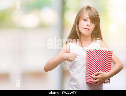 Giovane biondo toddler tenendo il popcorn pack con sorpresa faccia puntare il dito a se stesso Foto Stock