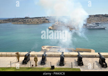 Lo sparo del cannone di mezzogiorno nella capitale Maltese di La Valletta. La cerimonia si tiene ogni giorno alla batteria a salve in alto Barracca gardens Foto Stock